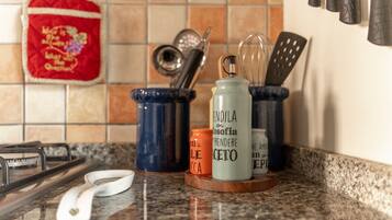 A kitchen counter with a gas stove, a white electric kettle, and various kitchen utensils in holders.