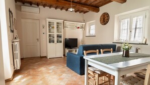 A cozy living area with a sofa, dining table, and TV. - At Chica's House - Lucca with Private Parking and Outdoor Space (Lucca)