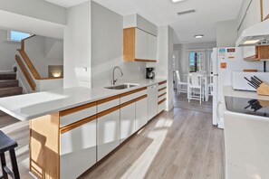 A modern kitchen with a central island, wooden cabinetry, and a view to the dining area.