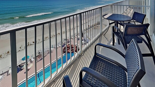 Un balcone con vista sull'oceano e sulla spiaggia. Sul balcone ci sono due sedie e un tavolo.