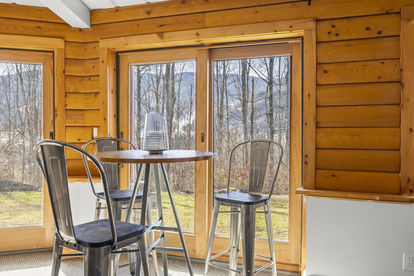 Une cabane en bois avec un coin repas comprenant deux chaises en métal et une table.
