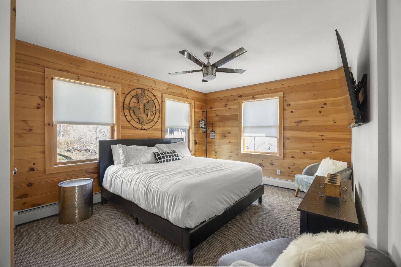 A bedroom with a bed, a ceiling fan, a globe decoration, and a window.