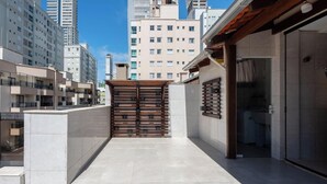 Un moderno complejo de apartamentos urbanos con entrada protegida, pisos de baldosas y vistas de edificios altos circundantes.