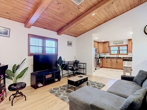 A living room with a television, a sofa, a coffee table, and a dining area with a chair and table. - Canal Front, Kayak, Paddle Board, Hot Tub, Convenient Location (Tampa)