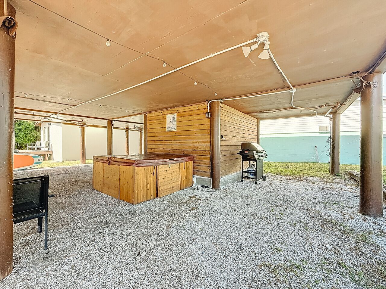 Un espace extérieur abrité, doté d’un bar en bois, de sièges et d’un sol en gravier.