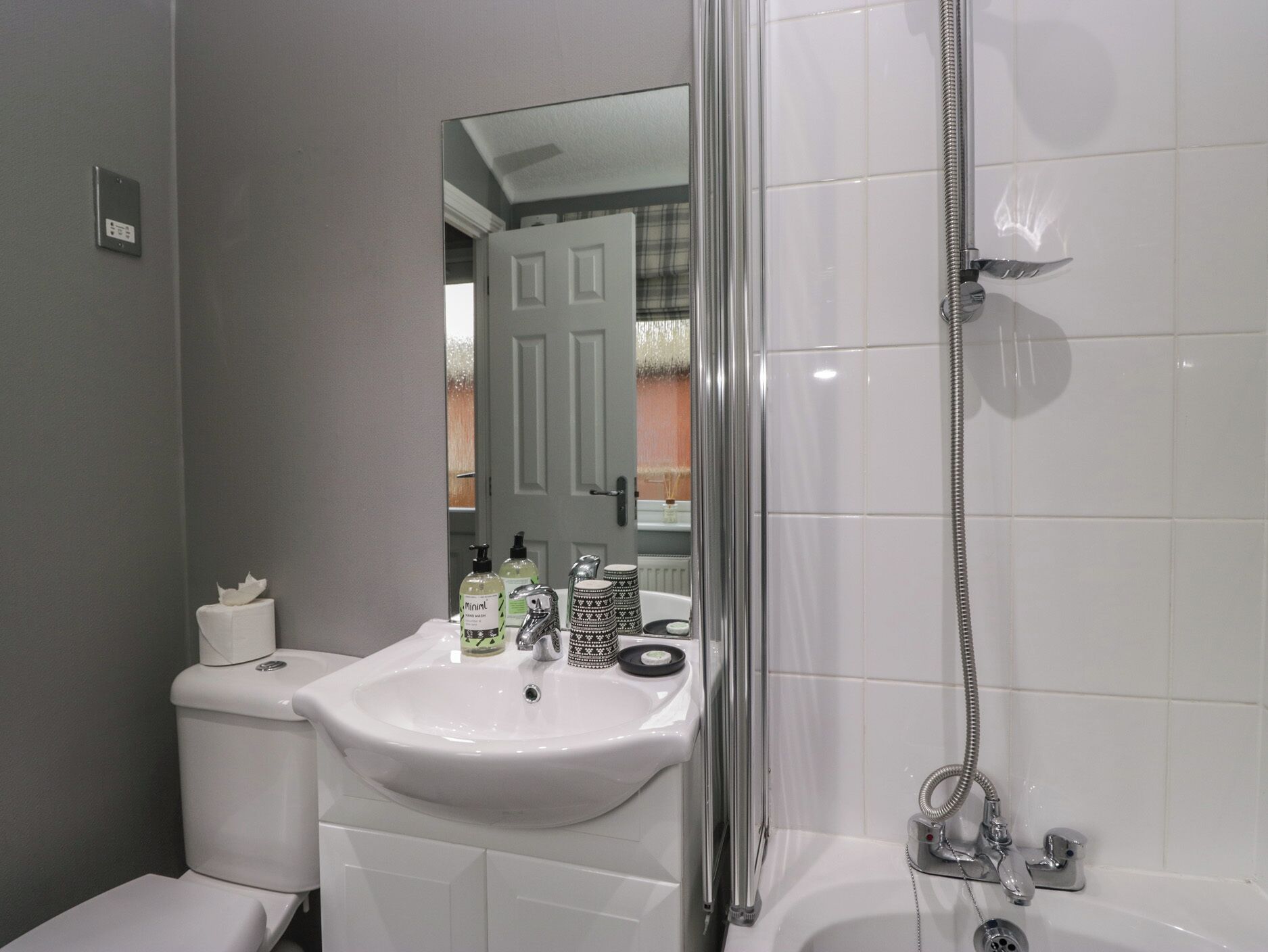 A bathroom with a white sink, toilet, and shower.