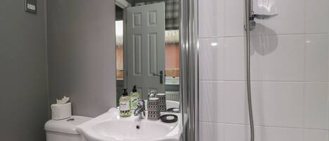 A bathroom with a white sink, toilet, and shower.