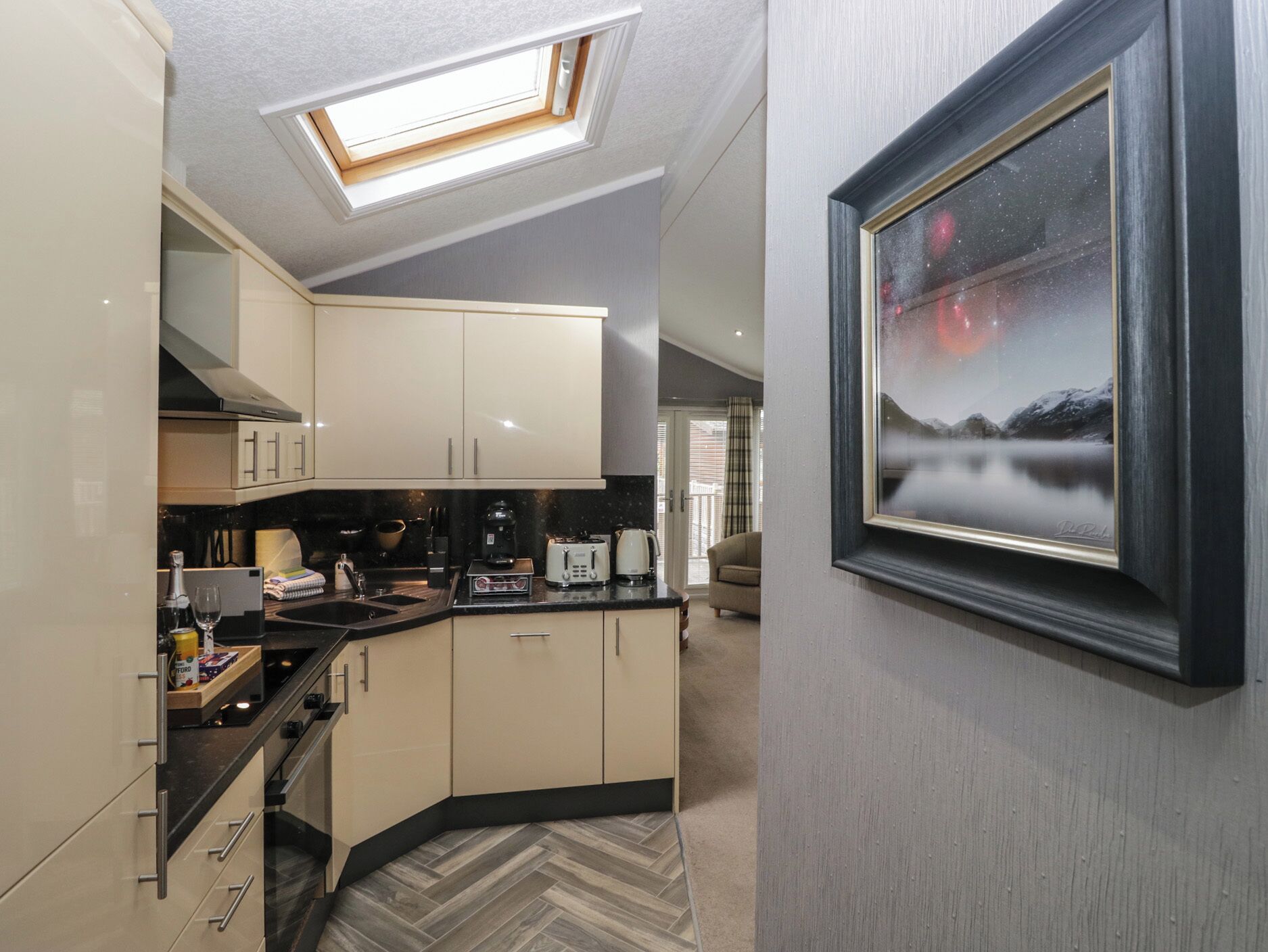 A modern kitchen with a skylight, a dining area, and a framed picture on the wall.