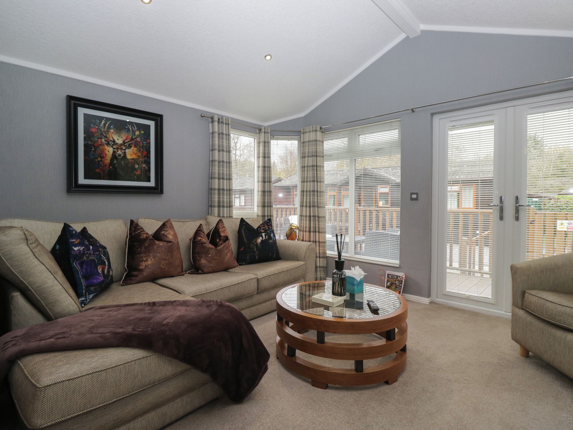A living room with a beige sofa, a round wooden coffee table, and a framed picture on the wall.