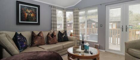 A living room with a beige sofa, a round wooden coffee table, and a framed picture on the wall.