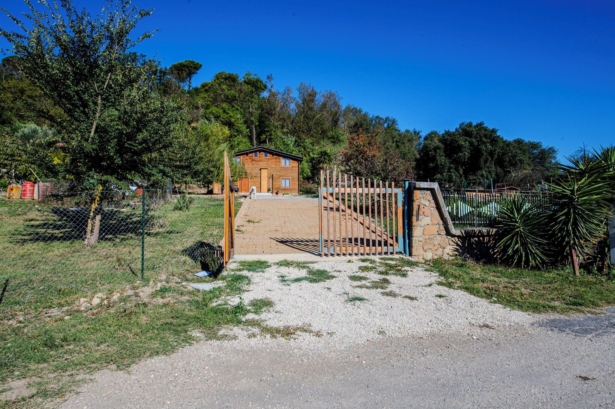 A rustic wooden house with a stone staircase leading to a gated entrance.