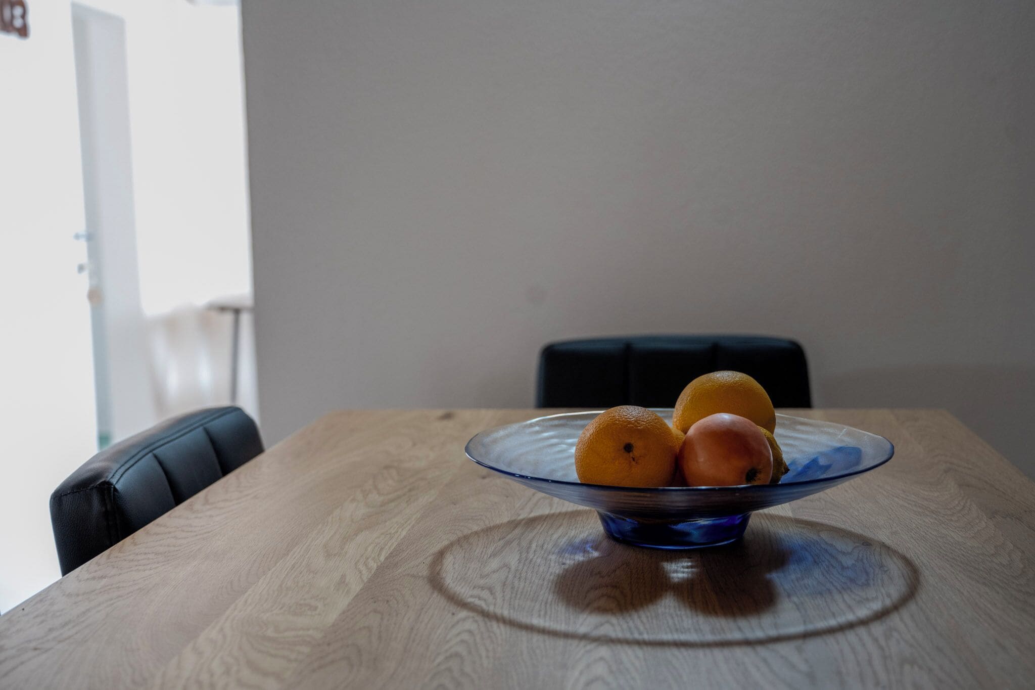 A dining table with a glass bowl containing oranges.