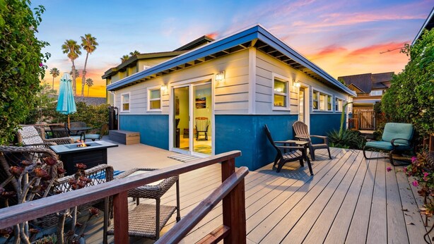 Una casa con terraza, mobiliario exterior y un brasero.