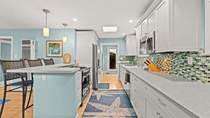 Una cocina moderna con armarios blancos, una isla central y un salpicadero colorido.