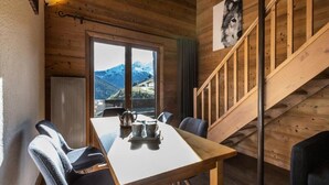 Un interior de madera con una mesa de comedor, sillas, vistas a montañas y una escalera.