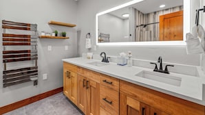 A modern bathroom with two sinks, a large mirror, wooden cabinets, and a towel rack. - Norwegian Log condo - Sleeps 8! (Steamboat Springs)