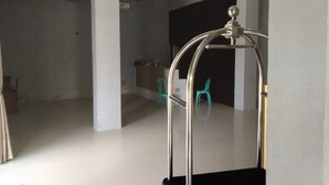 Une pièce spacieuse avec une grande structure métallique, qui pourrait être un élément décoratif ou un meuble, et un comptoir d’accueil avec une chaise en arrière-plan.
