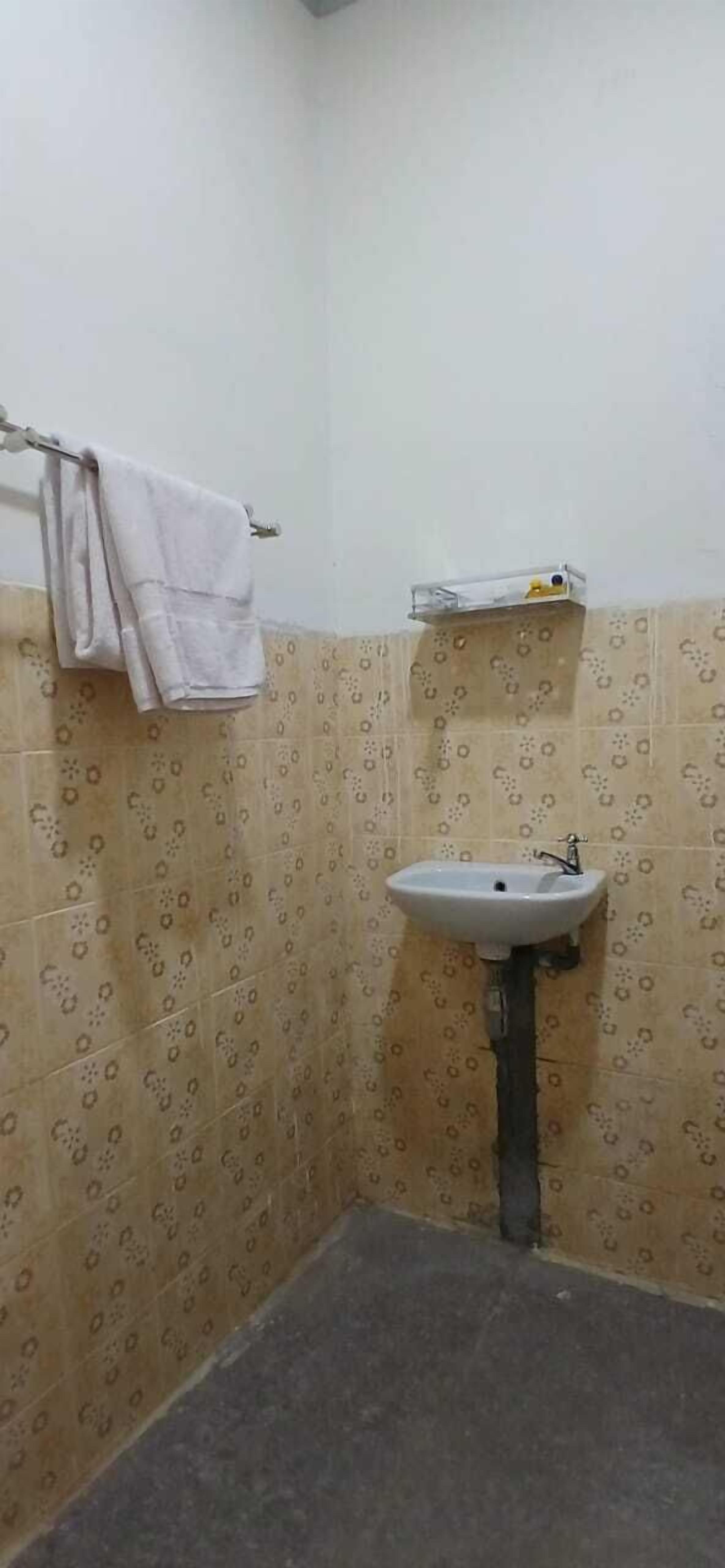A small bathroom with a sink, a towel rack, and patterned tiles.