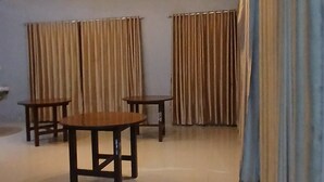 Une pièce spacieuse avec un plafond haut, trois lampes suspendues, une table en bois et deux chaises.