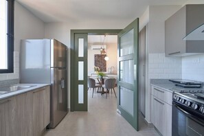 A modern kitchen with a dining area, a refrigerator, stove, and a window.