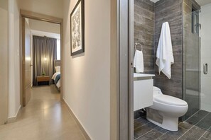 Een moderne badkamer met een glazen douchecabine, een wit toilet en een handdoekrek.