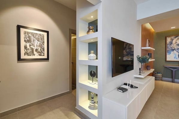A modern interior with a framed black and white photo, a flat-screen TV, and decorative shelves.