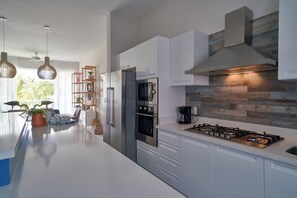 A modern kitchen with white cabinetry, a stainless steel range, and a wood-textured backsplash.