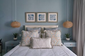 A neatly made bed with patterned pillows, a headboard, and two wall-mounted lamps. - {3BR~Beach~Condo}@LakeView PlayaBonita +Pool+LUX (Las Terrenas)