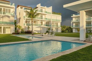 A modern hotel with a swimming pool, multiple balconies, and a well-maintained lawn. - {3BR~Beach~Condo}@LakeView PlayaBonita +Pool+LUX (Las Terrenas)