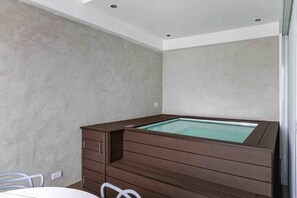 Ein Zimmer mit einer eingebauten Whirlwanne, einem weißen Tisch und Stühlen.