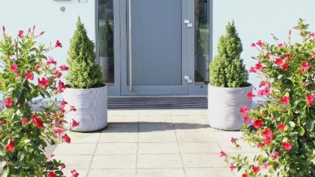 A building entrance with a grey door, potted plants, and a clear sky. - Lorenzhaus Exclusive Residence: Deluxe apartment with 3 bedrooms (Sankt Lorenz)