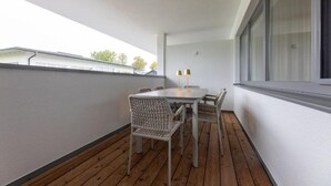 A balcony with a wooden floor, a white table with chairs, and two lamps. - Lorenzhaus Exclusive Residence: Deluxe apartment with 3 bedrooms (Sankt Lorenz)