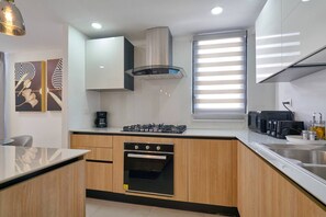 A modern kitchen with a gas stove, oven, and coffee maker. - ®2BR{The~City~Center}@DTown +Pool+Gym NearCecilip (Santo Domingo)