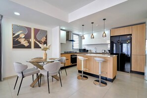 A modern kitchen with a central island, bar stools, pendant lighting, and artwork on the walls. - ®2BR{The~City~Center}@DTown +Pool+Gym NearCecilip (Santo Domingo)