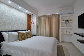 A modern bedroom with a large bed, a wall-mounted TV, and a built-in shelf with decorative items. - ®2BR{The~City~Center}@DTown +Pool+Gym NearCecilip (Santo Domingo)
