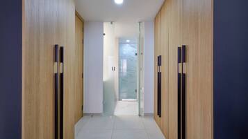 Un pasillo con paneles de madera y suelo de baldosas, que conduce a una puerta de cristal.