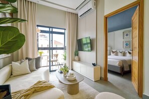 Ein modernes Hotelzimmer mit einer Couch, einem Couchtisch, einem Fernseher und einem Bett.