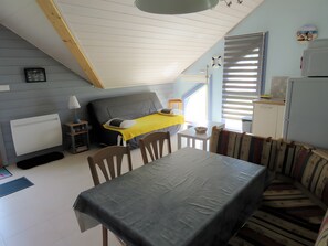 Ein gemütliches Schlafzimmer im Dachgeschoss mit einem Bett, einem kleinen Tisch und einer Couch.