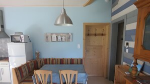 Une cuisine avec un coin repas, un four à micro-ondes, un meuble en bois et une porte.