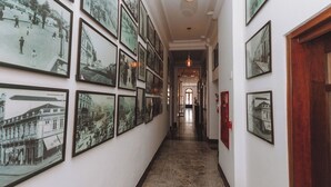 A hallway with multiple framed historical photographs on the walls, leading to a door at the end.