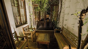A wooden deck with benches and a table, surrounded by walls with climbing plants. - Where Heritage Charm Meets Modern Comfort in Curitiba — Perfect for Groups (State of Paraná)