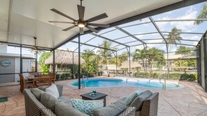 A covered outdoor area with a pool, seating, and a ceiling fan. - Villa Palma Encantada Gulf Access & Pet Friendly (Cape Coral)