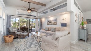 A spacious living room with a large window, a ceiling fan, and a cozy seating area. - Villa Palma Encantada Gulf Access & Pet Friendly (Cape Coral)