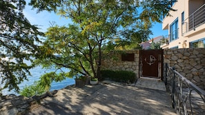 A coastal property with a stone wall, a metal gate, and a view of the sea.