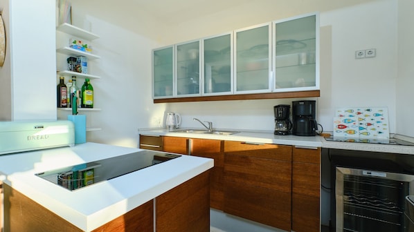 A modern kitchen with a built-in oven, a coffee maker, and a refrigerator.
