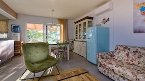 A compact living space with a dining area, a sofa, a kitchen with a blue refrigerator, and a water dispenser.