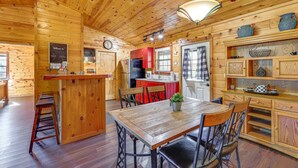 Interior de una cabaña de madera con cocina, comedor y barra.