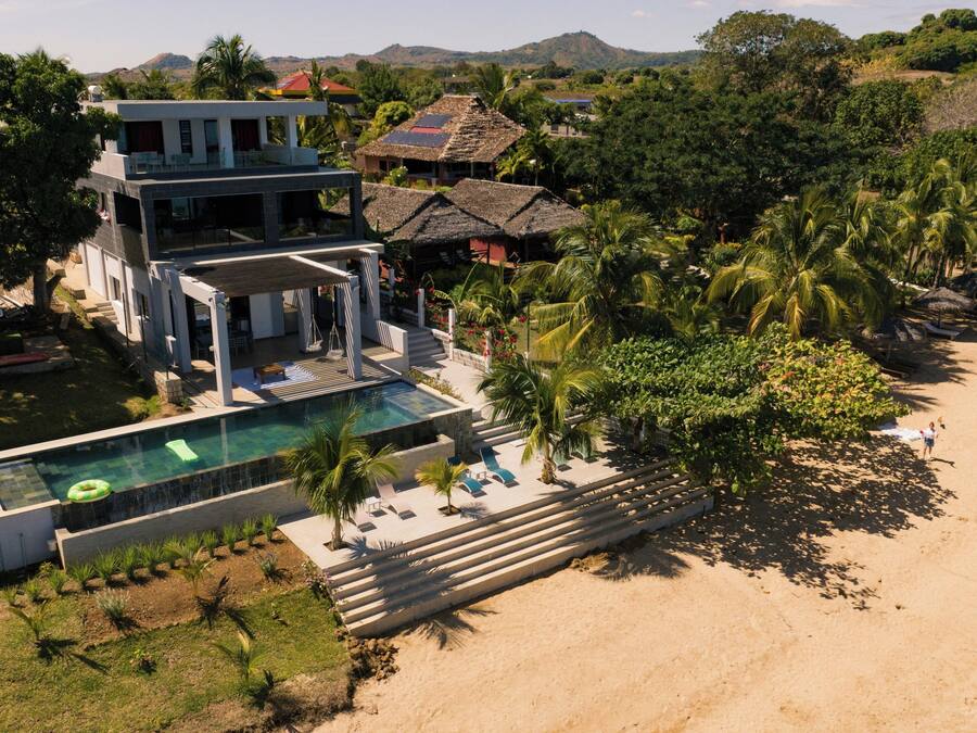 A modern resort with a pool, beach access, and tropical landscaping.