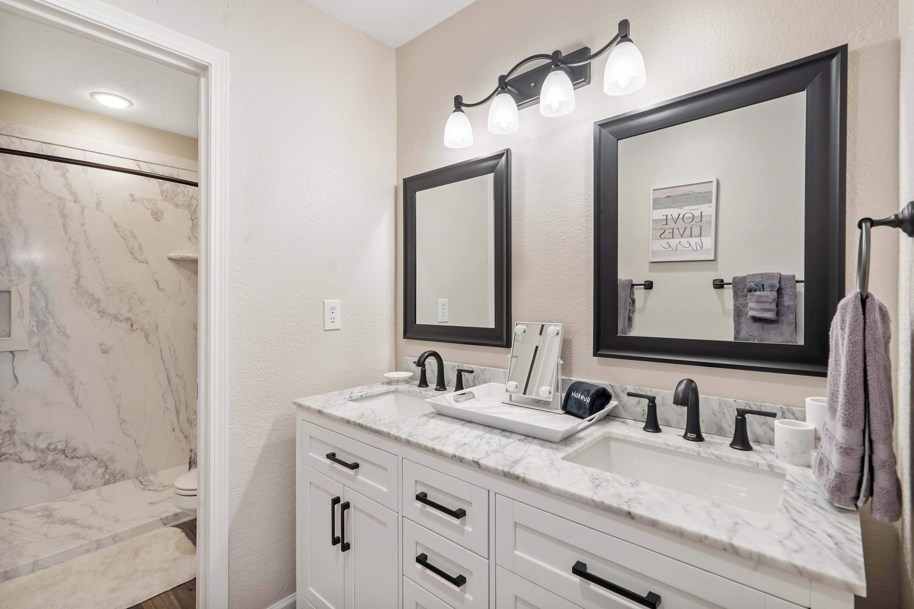 A bathroom with a double sink, vanity, and a large mirror.