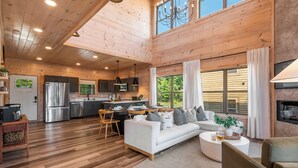 A spacious wooden cabin interior with a kitchen, dining area, and living room. - Modern Smoky Mountain Cabin Near Dollywood – Indoor Pool, Hot Tub & Arcade Fun (Pigeon Forge)